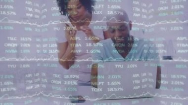 Animation of data processing over man and woman using laptop and smartphone. Global business, finance, computing, connections and data processing concept digitally generated video.