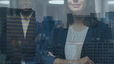 Animation of multiracial smiling coworkers standing arms crossed in office over buildings. Digital composite, multiple exposure, entrepreneurs, skyscrapers, business, abstract, technology concept.