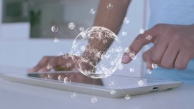Animation of globe of profile icons spinning over mid section of man using digital tablet at home. Global networking and business technology concept