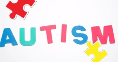 Animation of autism text with puzzle pieces on white background. Autism awareness month and digital interface concept digitally generated video.