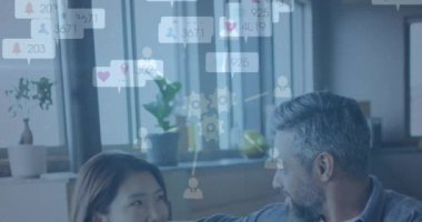 Animation of social media icons over biracial couple talking to each other at home. Social media networking technology