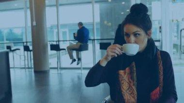 Animation of thumbs up icons over caucasian woman drinking coffee and using laptop at cafeteria. Digital composite, multiple exposure, social media, drink, likes, office, business and technology.