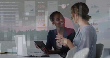 Animation of financial data processing over diverse businesswomen in office. Global business, finance, computing and data processing concept digitally generated video.