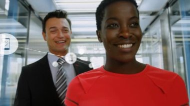 Animation of connected icons over diverse coworkers smiling and discussing while walking in corridor. Digital composite, multiple exposure, communication, teamwork and business concept.