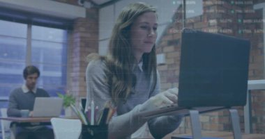 Animation of trading board and graphs over caucasian woman working on laptop at office. Digital composite, multiple exposure, report, stock market, business, abstract and technology concept.