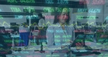 Animation of trading board and graphs over asian businesswoman using digital tablet in office. Digital composite, multiple exposure, stock market, investment, report, finance and technology concept.