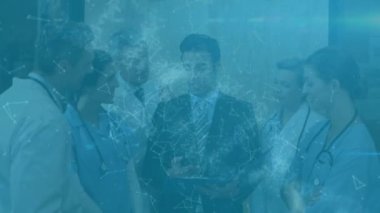 Animation of network of connections over caucasian businessman talking to a team of medical doctors. Healthcare and business technology concept