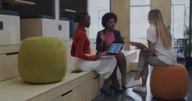 Animation of connected icons, numbers, letters, symbols on diverse coworkers discussing reports. Digital composite, multiple exposure, globalization, security, communication and technology concept.