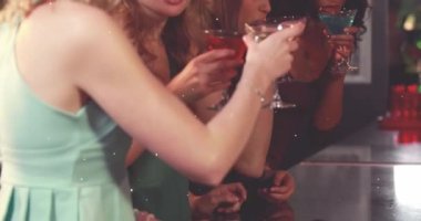Animation of white particles over group of diverse friends enjoying their drinks together at a bar. Party and nightlife concept