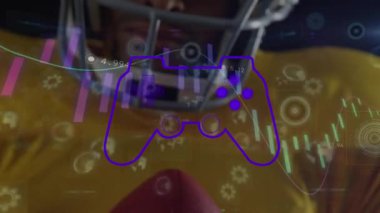 Animation of data processing with gamepad icon over african american male american football player. Global sport, computing and digital interface concept digitally generated video.