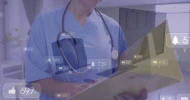 Animation of social media icons over caucasian female doctor reading reports at hospital. Social media networking and healthcare technology concept