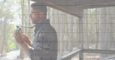 Animation of graphs and numbers over caucasian male photographer clicking photos through window. Digital composite, multiple exposure, forest, report, business, camera, memories and technology.
