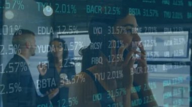 Animation of trading board over biracial businesswoman talking on smartphone in office. Digital composite, multiple exposure, stock market, investment, abstract and technology concept.