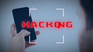 Animation of scope scanning over hacking text banner over rear view of a man using smartphone. Cyber security and business technology concept
