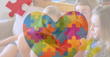Animation of puzzle and autism awareness month text over caucasian girls using tablet. Autism awareness month, celebration and digital interface concept digitally generated video.