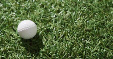 Close up of golf ball on grass, copy space, slow motion. Golf, sport and hobby concept.