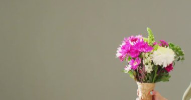 Video of woman holding bunch of flowers with copy space on grey background. Mothers day, nature and spring concept.