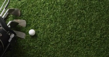 Close up of golf clubs and ball on grass, copy space, slow motion. Golf, sport and hobby concept.