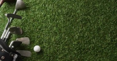Close up of golf clubs and ball on grass, copy space, slow motion. Golf, sport and hobby concept.