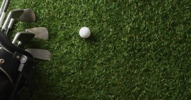 Close up of golf clubs and ball on grass, copy space, slow motion. Golf, sport and hobby concept.