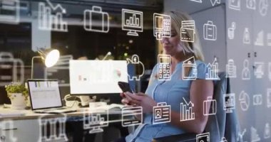Animation of icons and data processing over caucasian businesswoman working in office. Global business, finances, computing and data processing concept digitally generated video.