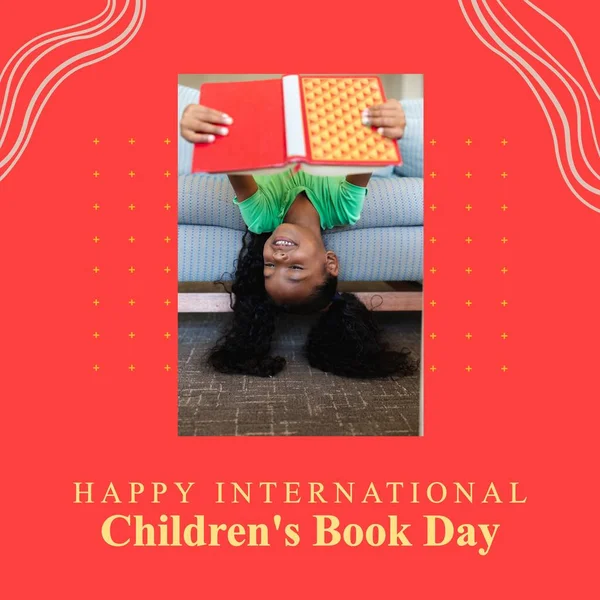 Composition of happy international children\'s book day text with african american girl reading book. International childrens\'s book day concept digitally generated image.