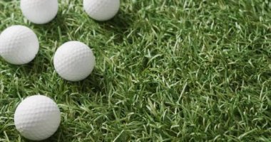 Close up of golf balls on grass, copy space, slow motion. Golf, sport and hobby concept.