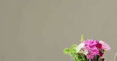 Video of woman holding bunch of flowers with copy space on grey background. Mothers day, nature and spring concept.