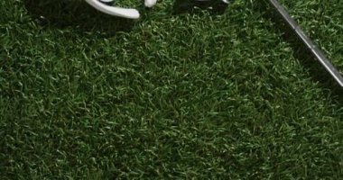 Close up of golf club, balls, glove and peaked cap on grass, copy space, slow motion. Golf, sport and hobby concept.