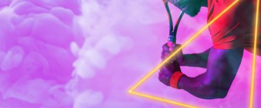 Midsection of african american male player holding racket by triangle on purple smoky background. Hand, tennis, illuminated, copy space, composite, sport, competition, shape, match, abstract.