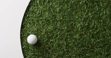 Close up of golf ball on grass with white background, copy space, slow motion. Golf, sport and hobby concept.