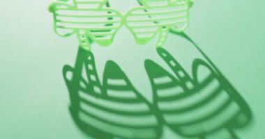 Video of st patrick's green shamrock glasses with copy space on green background. St patrick's day, irish tradition and celebration concept.