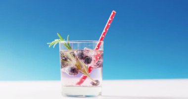 Close up of transparent drink with bluberries on blue background. Cocktail day, party and celebration concept.