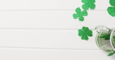 Video of st patrick's green shamrock and green beer with copy space on white background. St patrick's day, irish tradition and celebration concept.