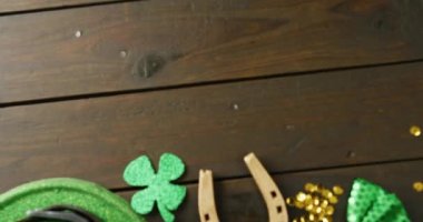 Video of st patrick's green hat, shamrock and horseshoe with copy space on wooden background. St patrick's day, irish tradition and celebration concept.