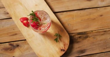 Close up of drink with strawberries on wooden board, with copy space. Cocktail day, party and celebration concept.