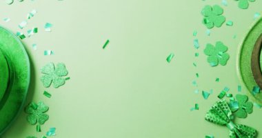Video of st patrick's green shamrock leaves and hat with copy space on green background. St patrick's day, irish tradition and celebration concept.