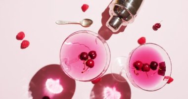 Close up of drinks with cherries and shaker on white background. Cocktail day, party and celebration concept.