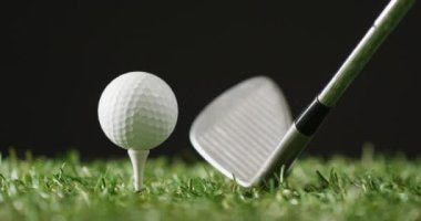 Close up of golf club and ball on grass and black background, copy space, slow motion. Golf, sport and hobby concept.