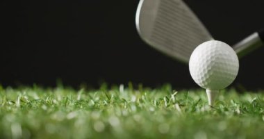 Close up of golf club and ball on grass and black background, copy space, slow motion. Golf, sport and hobby concept.