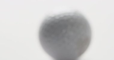Close up of golf ball on white background, copy space, slow motion. Golf, sport and hobby concept.