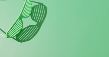 Video of st patrick's green glasses with copy space on green background. St patrick's day, irish tradition and celebration concept.