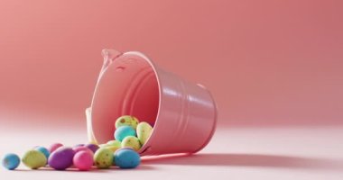 Bucket with colorful easter eggs on pink background with copy space. Easter, tradition and celebration concept.
