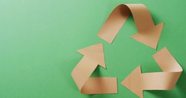 Close up of recycling symbol of paper arrows on green background, with copy space. Global recycling, ecology and nature concept.