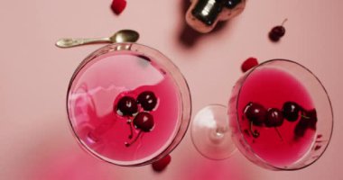Close up of drinks with cherries and shaker on white background. Cocktail day, party and celebration concept.
