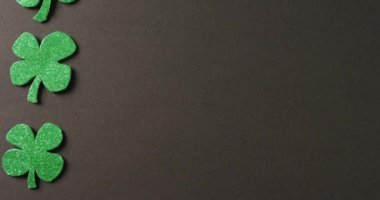 Animation of st patrick's green shamrock leaves with copy space on black background. St patrick's day, irish tradition and celebration concept digitally generated video