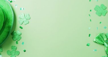 Video of st patrick's green shamrock leaves and hat with copy space on green background. St patrick's day, irish tradition and celebration concept.