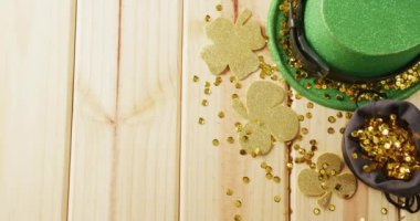 Video of st patrick's green hat, shamrock and bow tie on wooden background. St patrick's day, irish tradition and celebration concept.