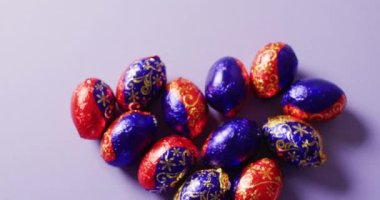 Close up of multiple chocolate easter eggs on purple background. Easter, tradition and celebration concept.