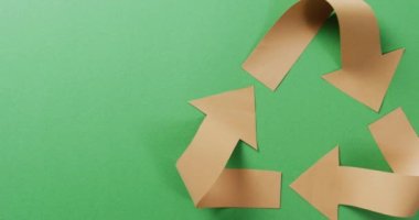 Close up of recycling symbol of paper arrows on green background, with copy space. Global recycling, ecology and nature concept.
